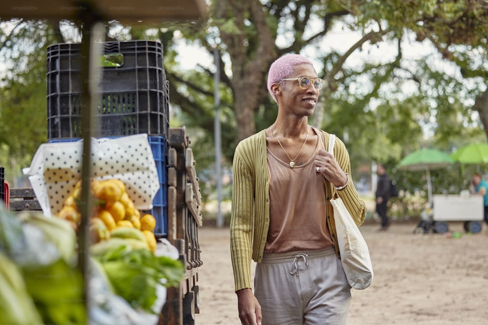 a man with a pink mohawk walking past a fruit stand