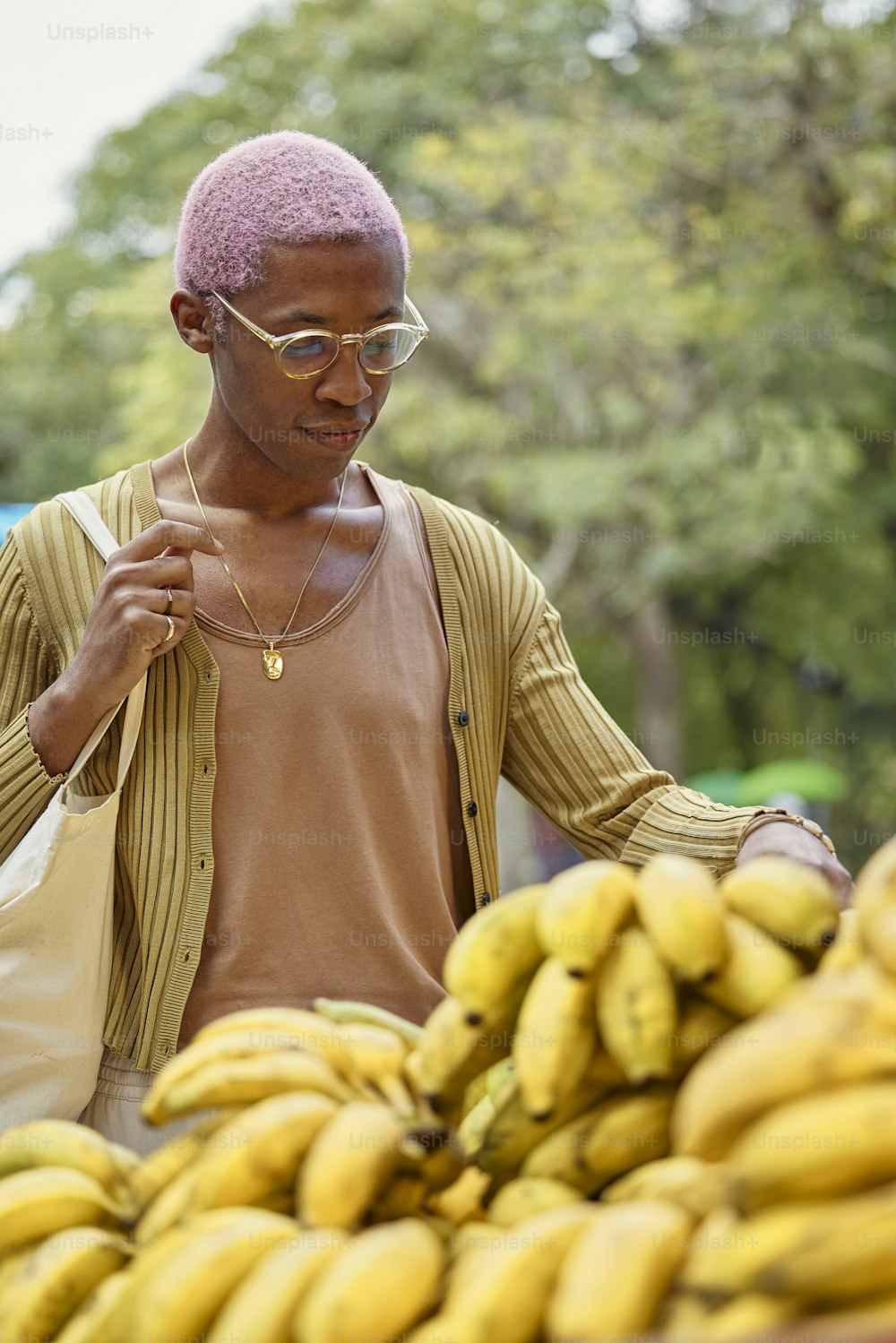 Un hombre parado frente a un montón de plátanos