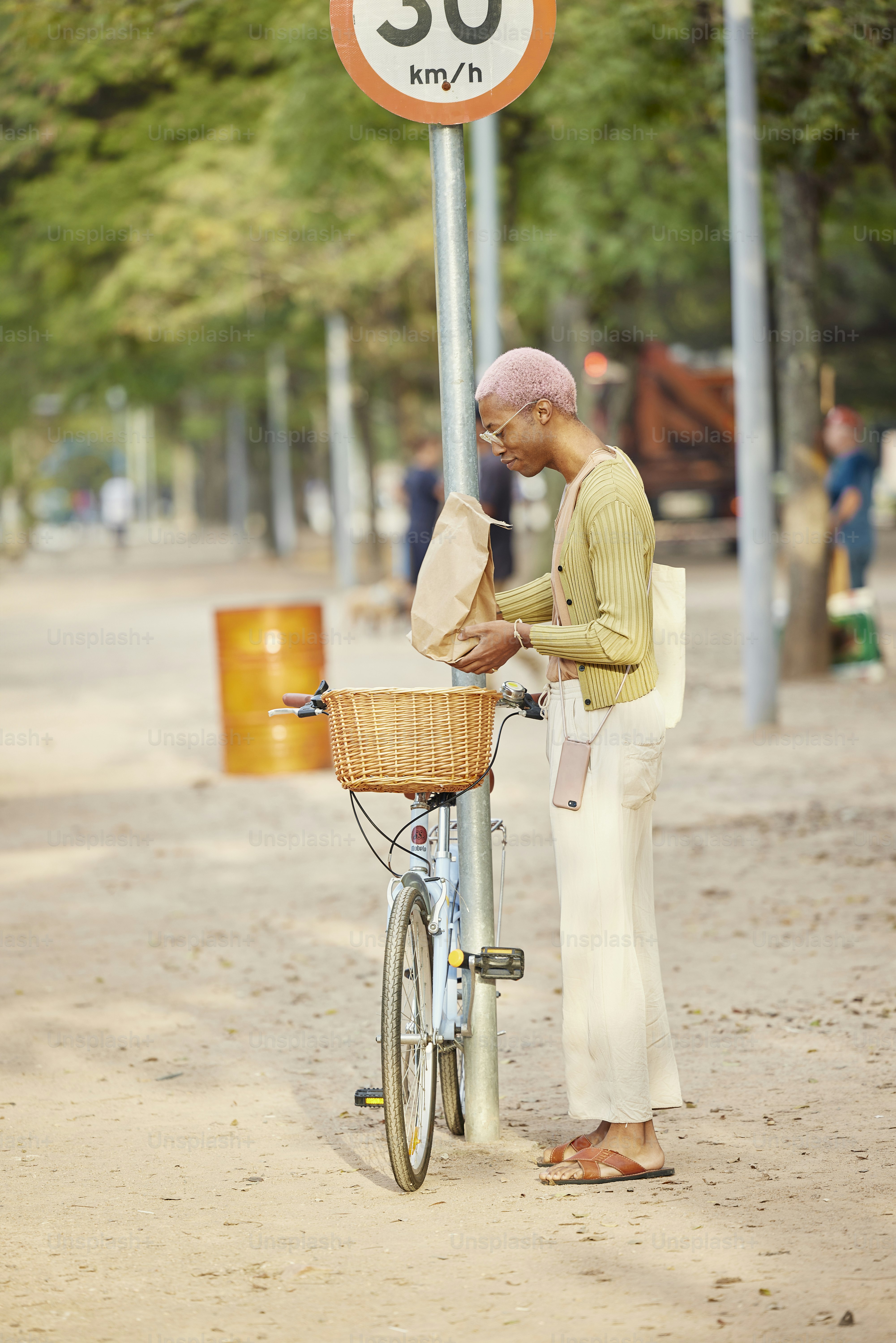 a man standing next to a bike next to a speed sign