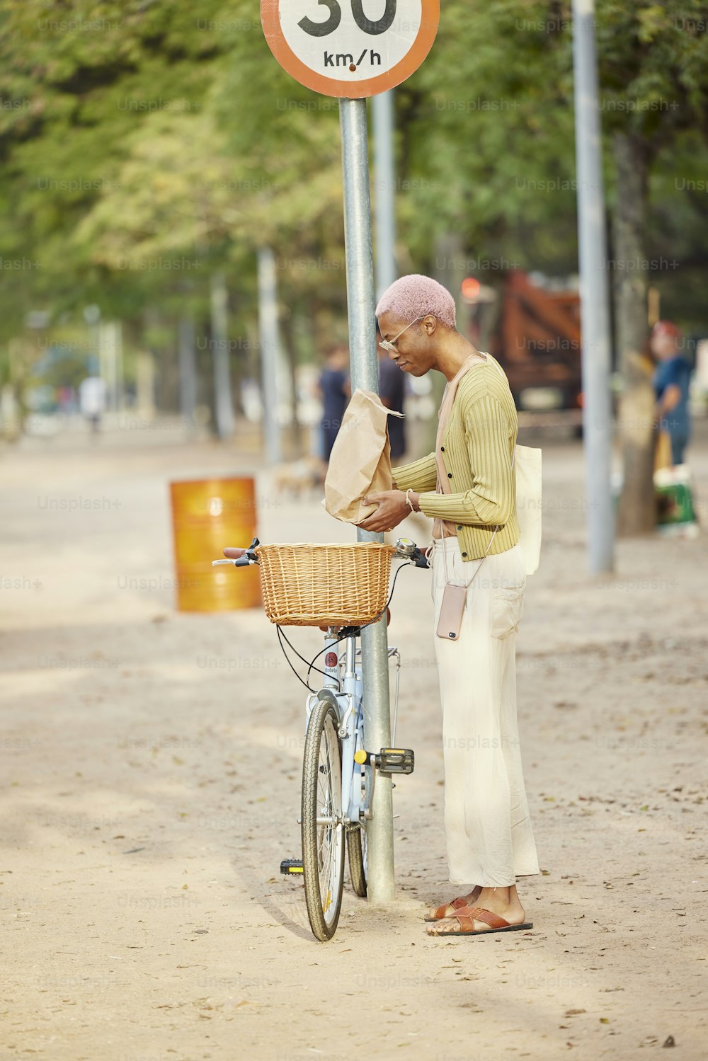 Un hombre parado junto a una bicicleta junto a una señal de velocidad