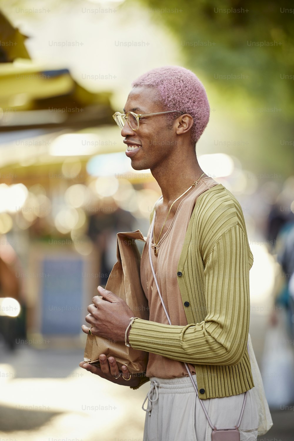 a man with pink hair and glasses holding a bag