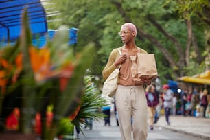 a man walking down a street holding a paper bag