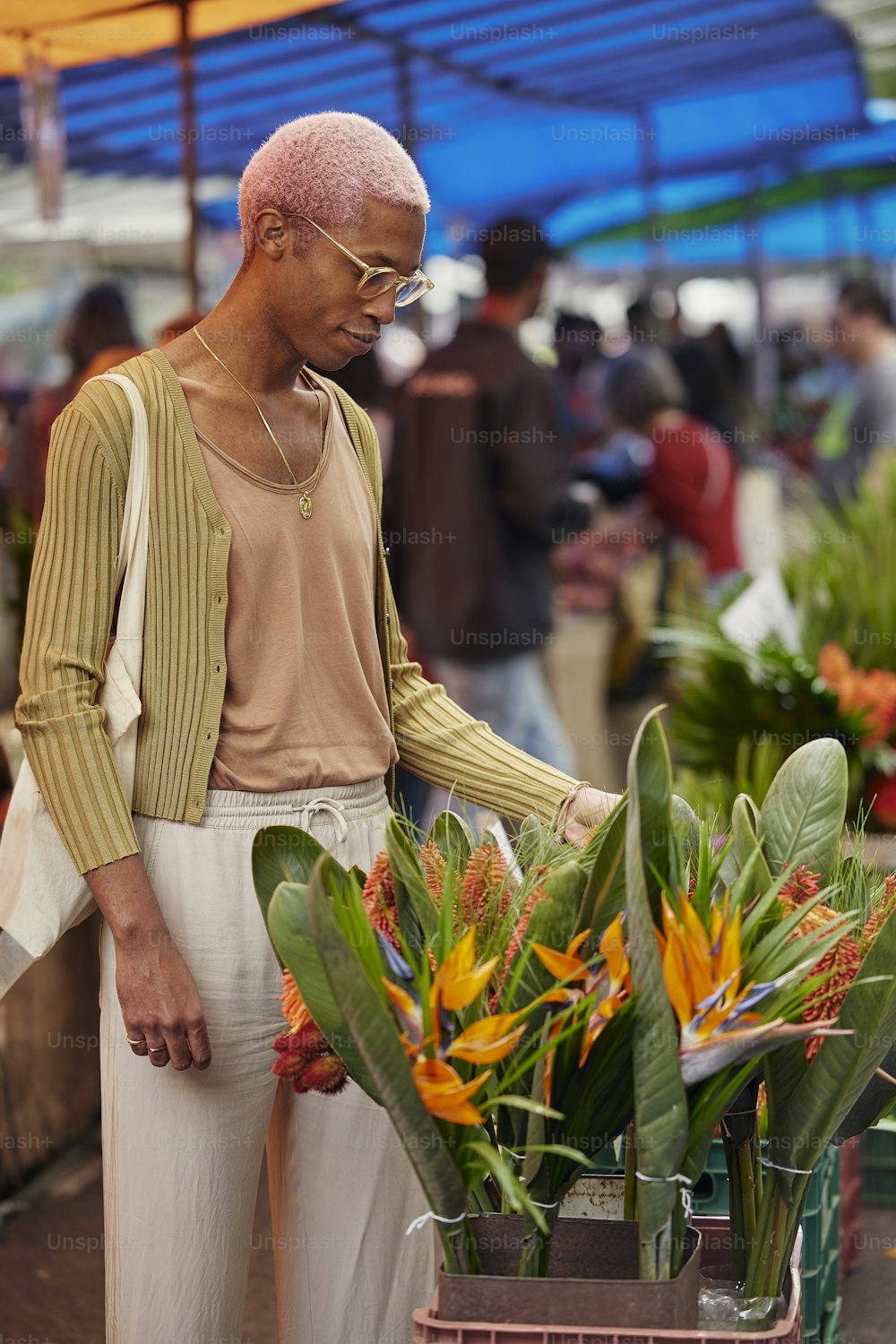 a man standing next to a bunch of flowers