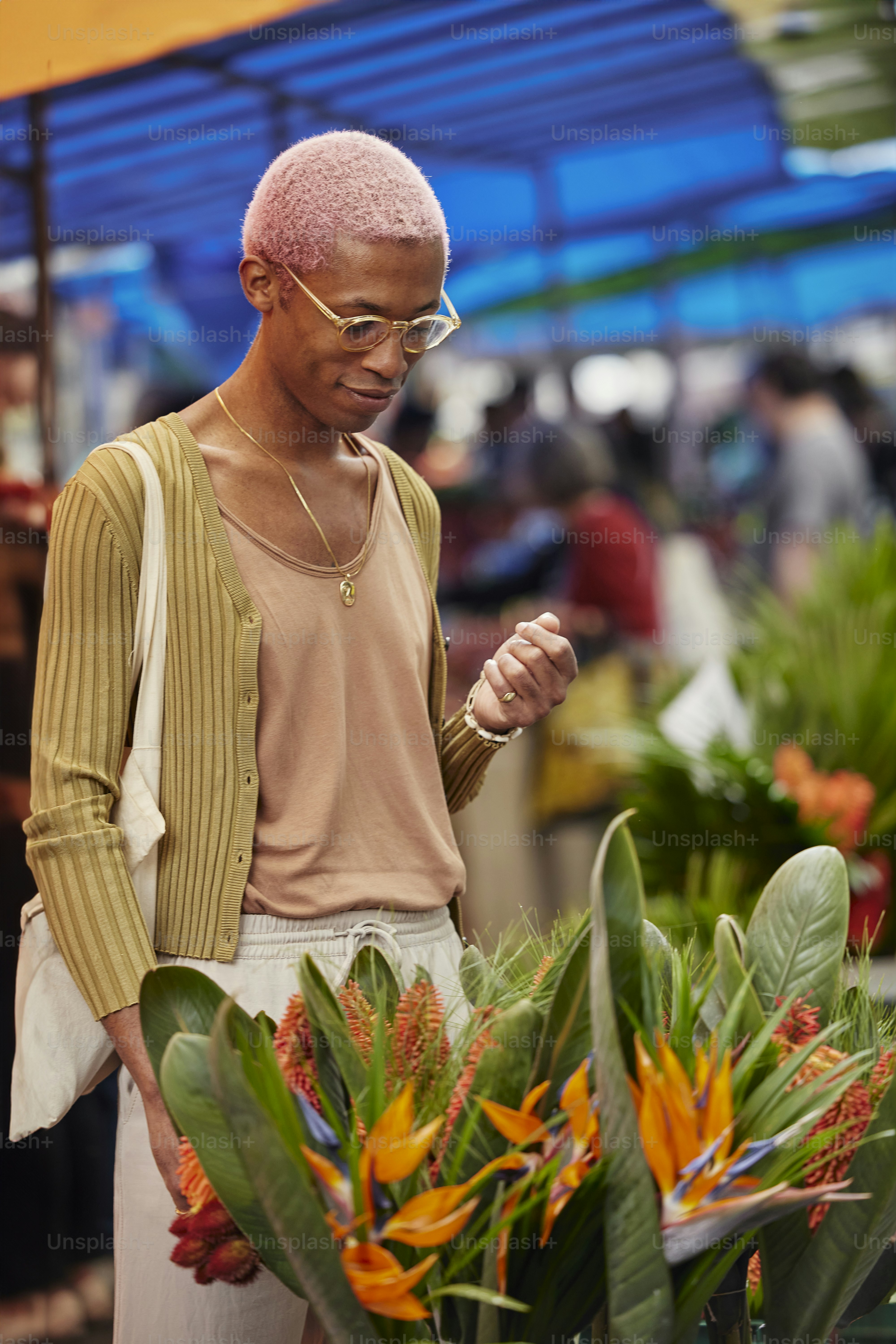 a man with pink hair standing next to a plant