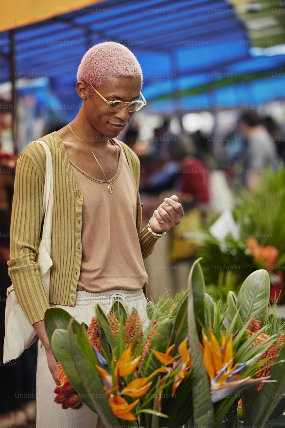 ein mann mit rosa haaren, der neben einer pflanze steht