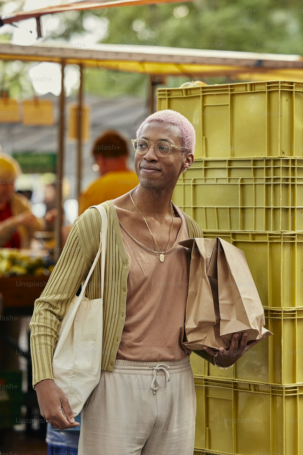 a man with pink hair standing next to a yellow container