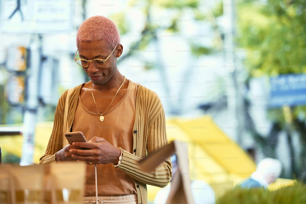 Un homme aux cheveux roses regarde son téléphone portable