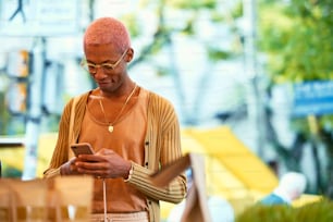 ピンクの髪の男が携帯電話を見ている