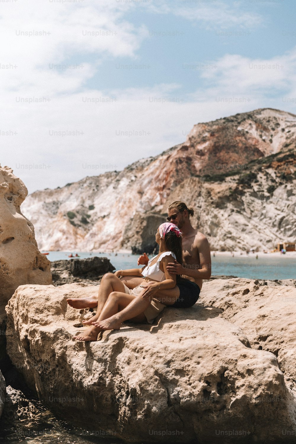 a man and a woman are sitting on a rock