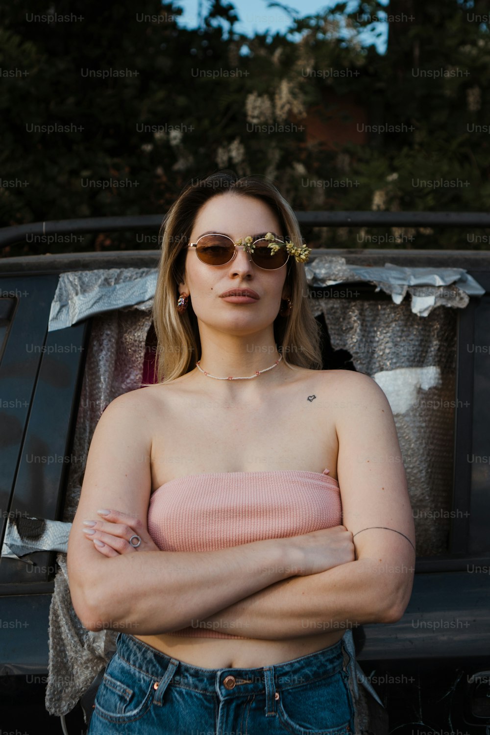 a woman with her arms crossed standing in front of a car