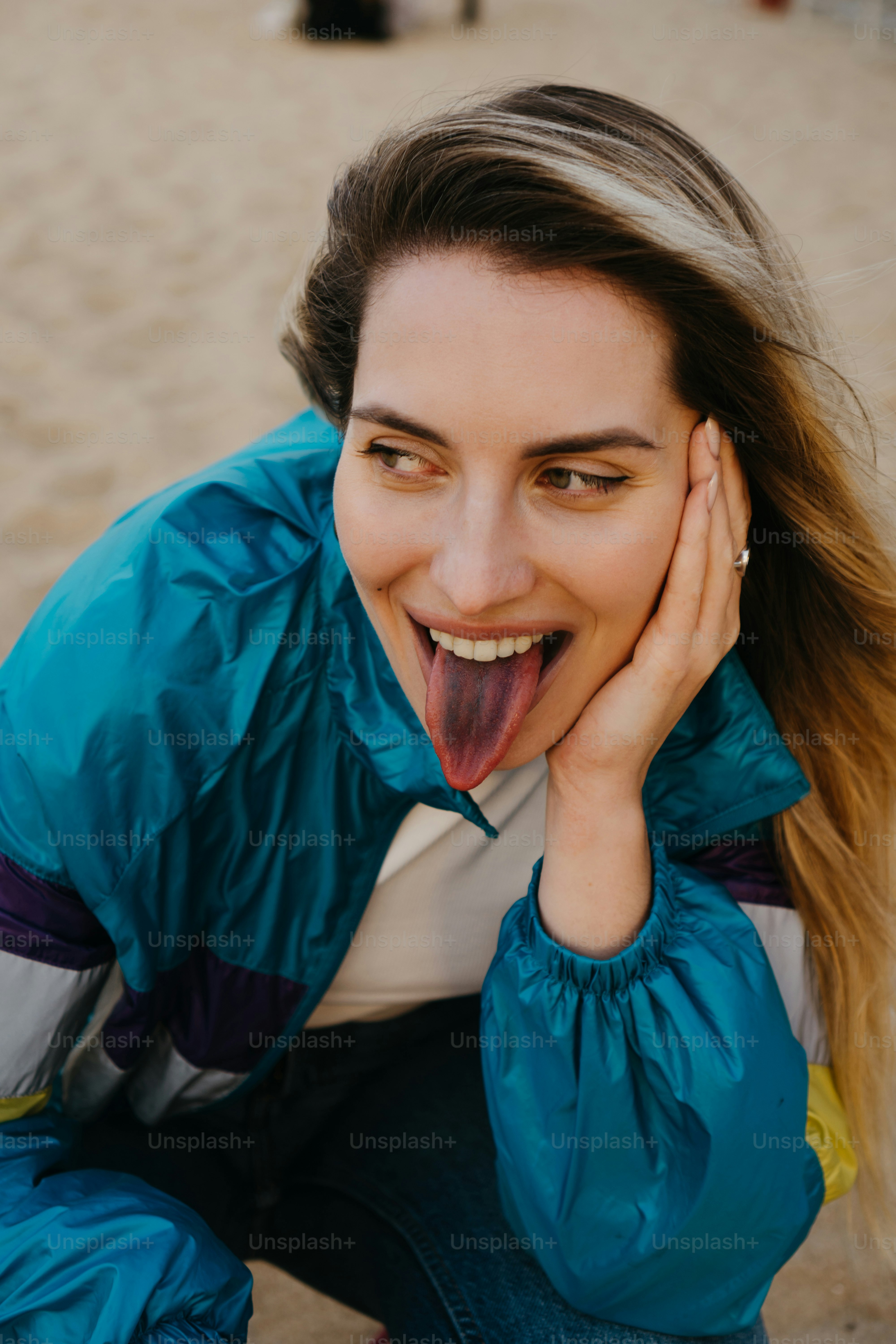 eine frau, die ein lustiges gesicht macht, während sie am strand sitzt