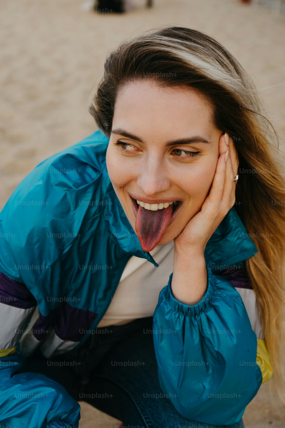una donna che fa una faccia divertente mentre è seduta sulla spiaggia