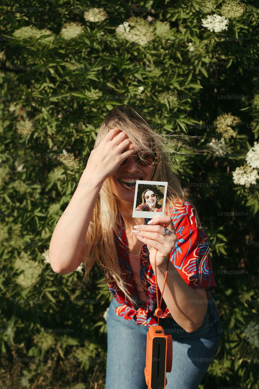 Una mujer sosteniendo una polaroid frente a su cara