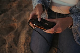 Une femme assise sur la plage tenant un téléphone portable