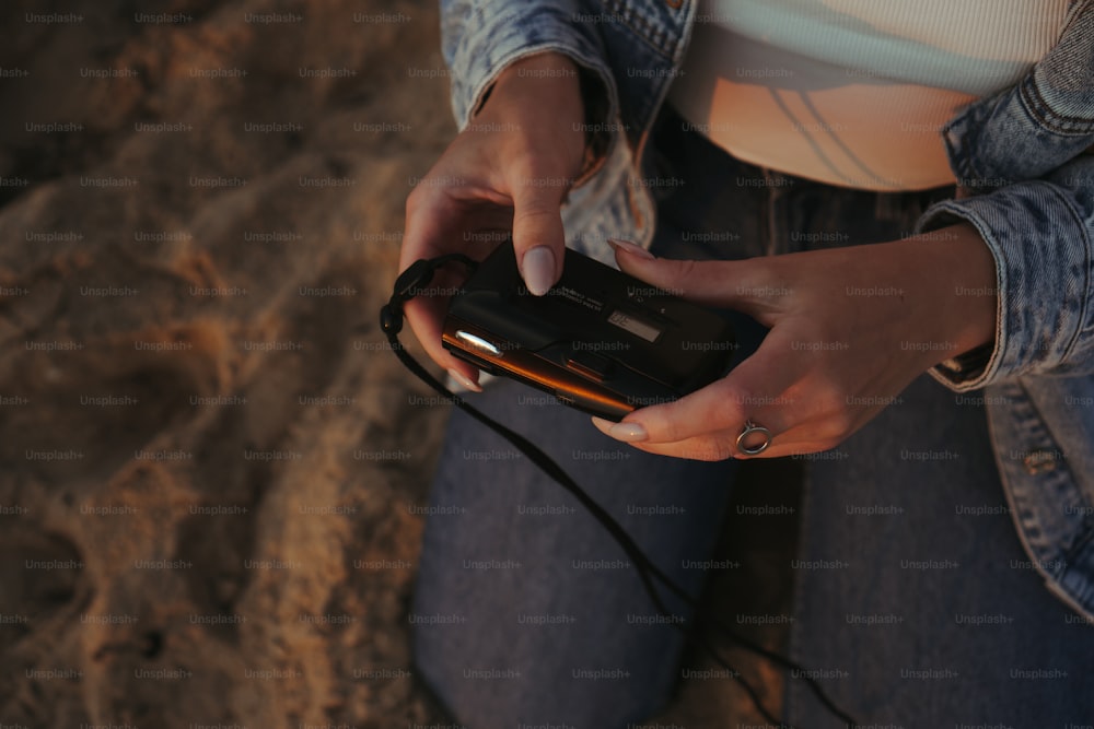 Una mujer sentada en la playa sosteniendo un teléfono celular