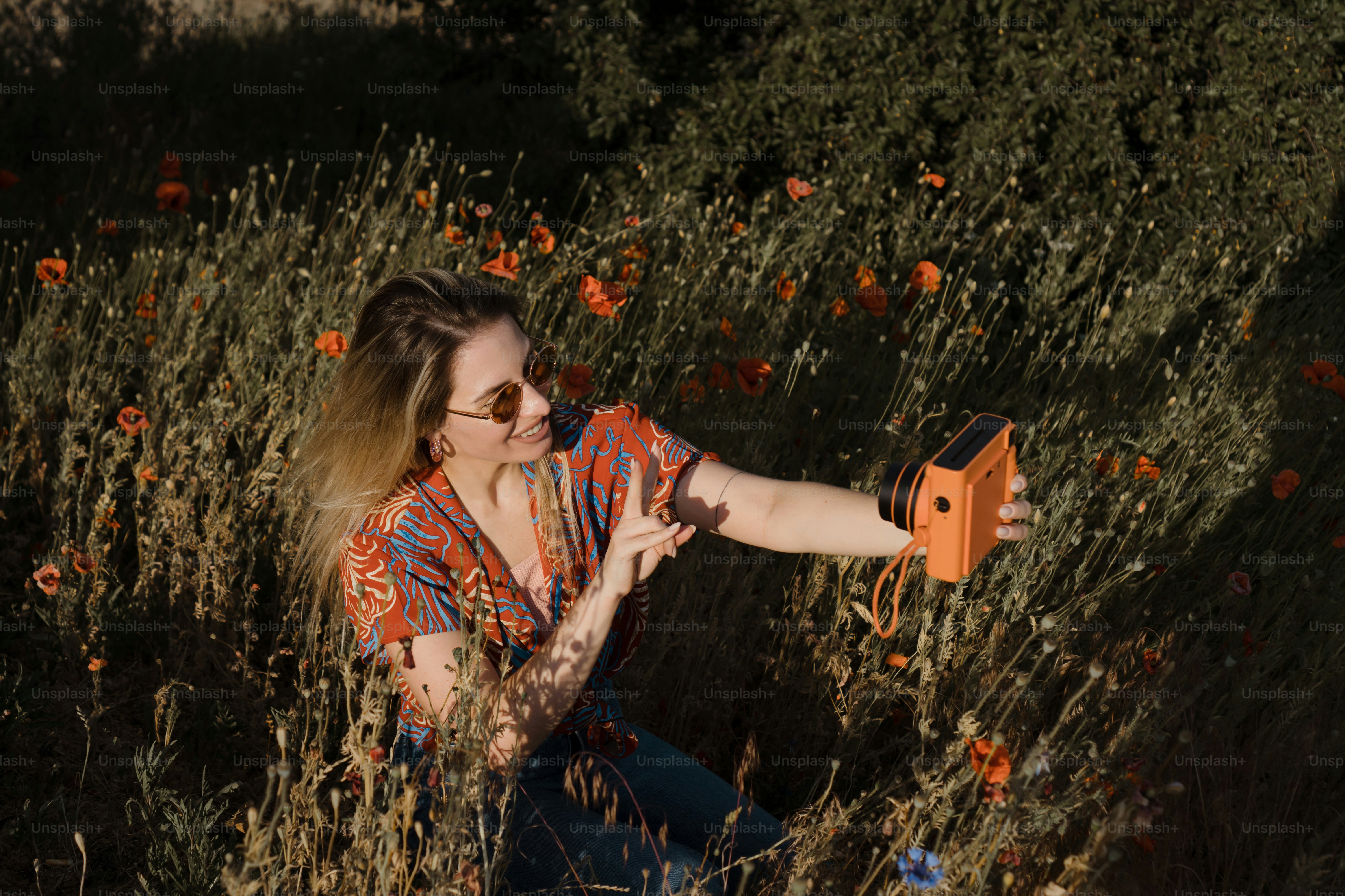 a woman sitting in a field of flowers holding an orange object