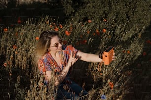 uma mulher sentada em um campo de flores segurando um objeto laranja