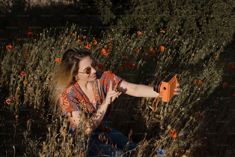 a woman sitting in a field of flowers holding an orange object