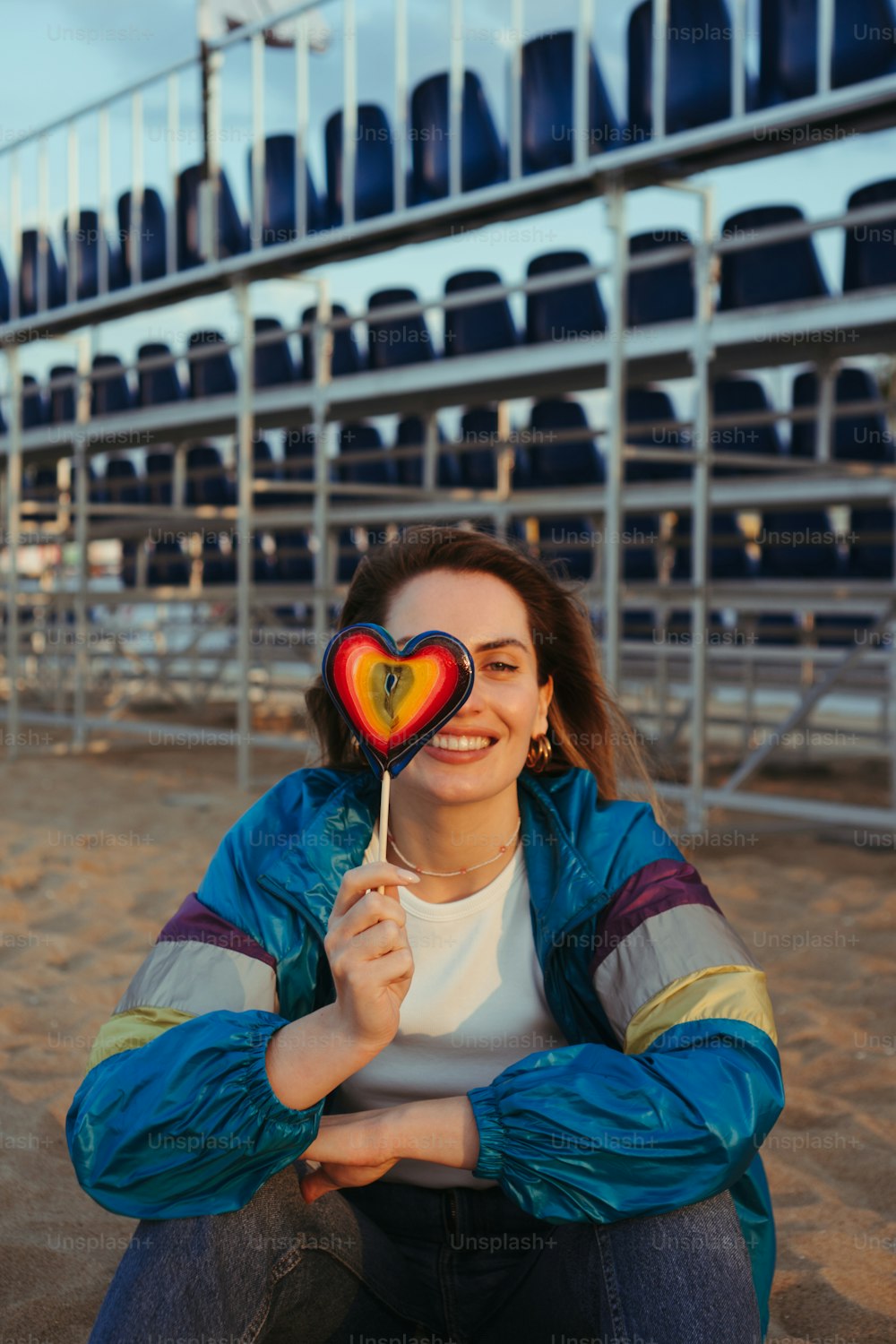 a woman holding a heart shaped lollipop in front of a stadium
