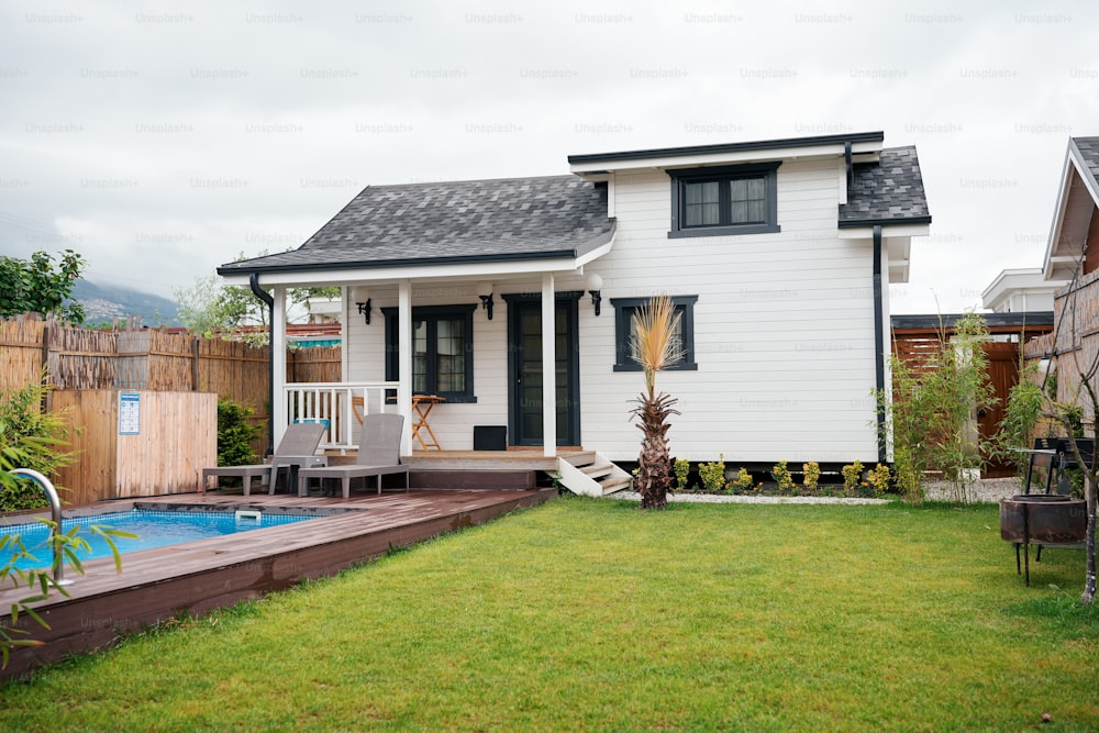 uma pequena casa branca com uma piscina no quintal