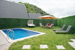 a backyard with a pool and lawn furniture