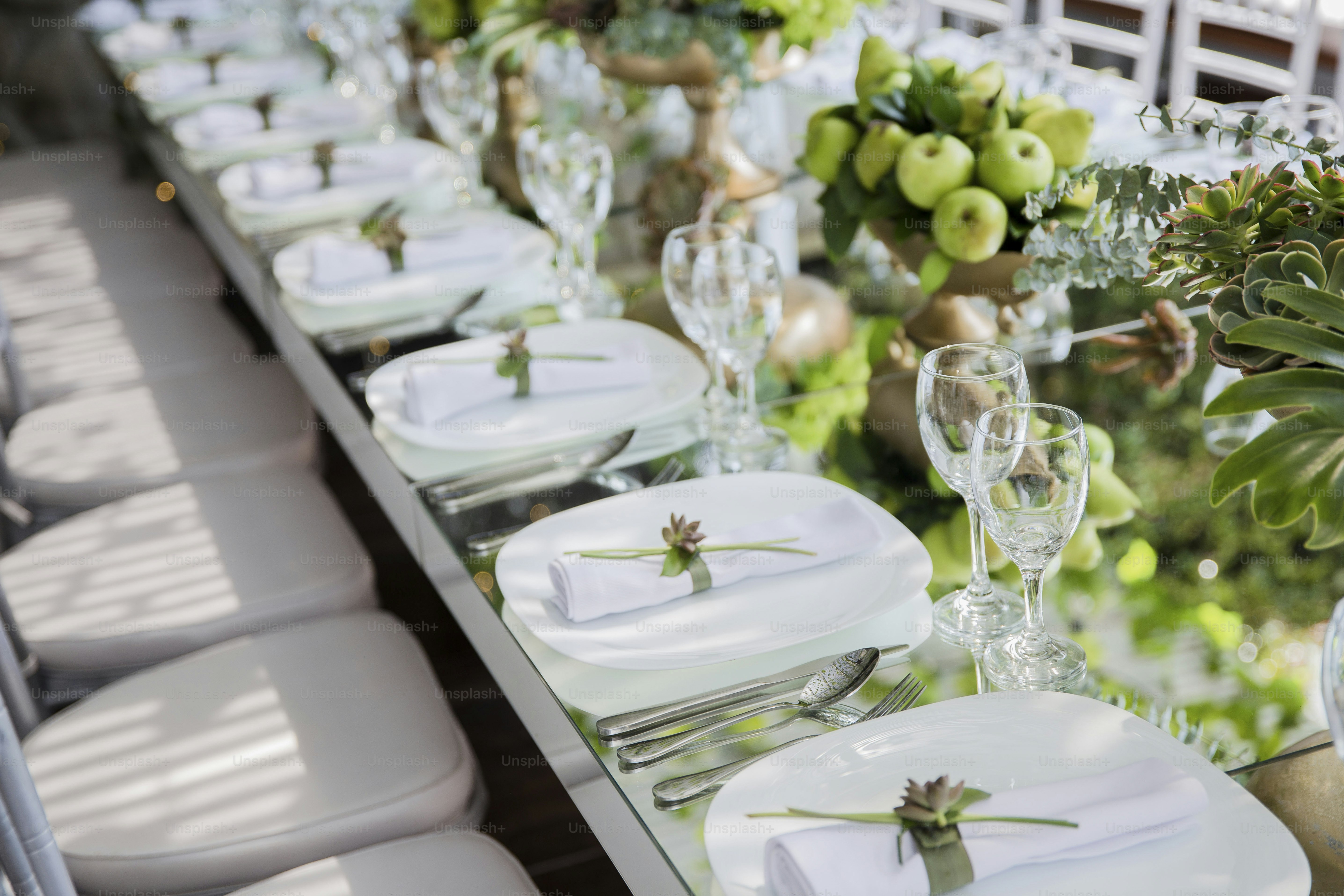 a long table is set with white plates and silverware