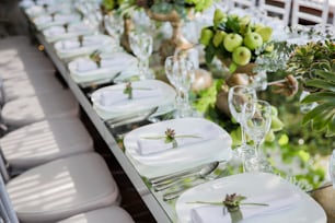 a long table is set with white plates and silverware
