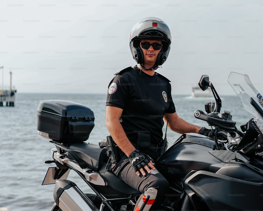 a man sitting on a motorcycle by the water