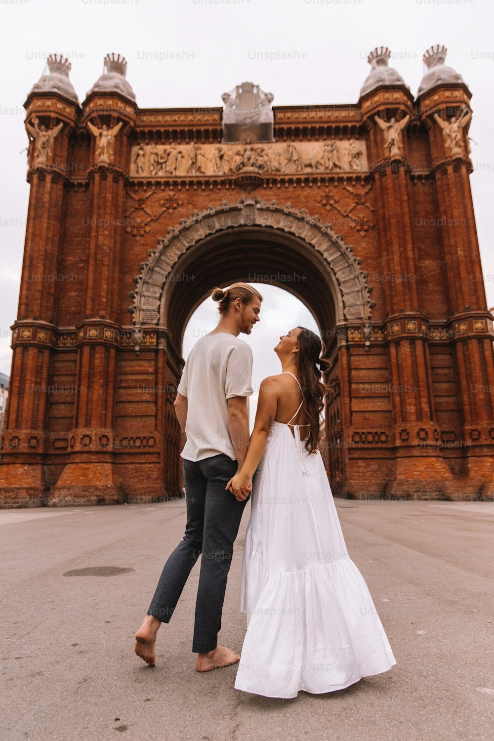 a man and a woman holding hands in front of an arch