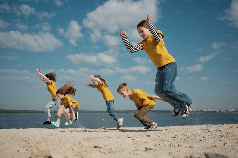 a group of kids jumping in the air on a beach