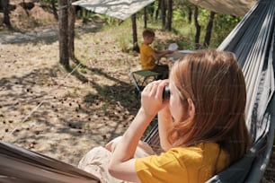 a woman sitting in a hammock talking on a cell phone