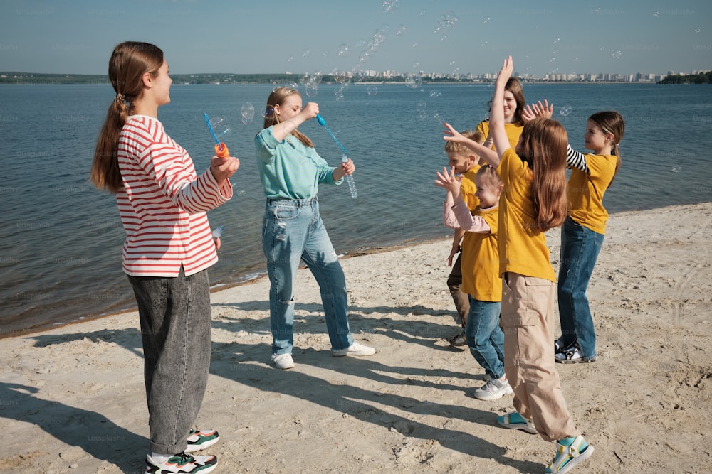 a group of young girls standing on top of a sandy beach