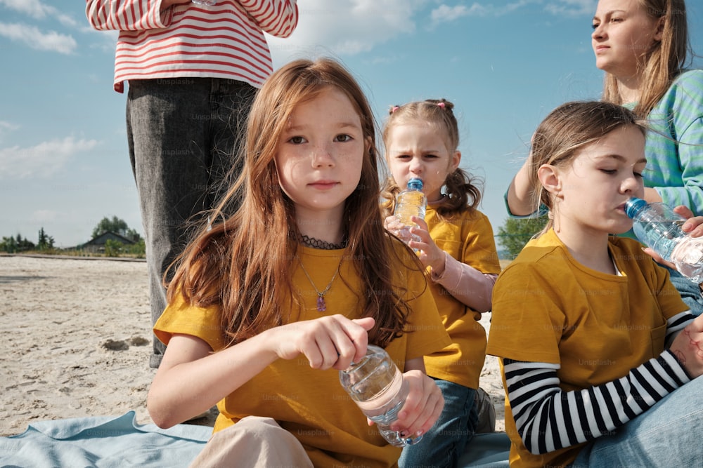 a group of young girls sitting on top of a sandy beach