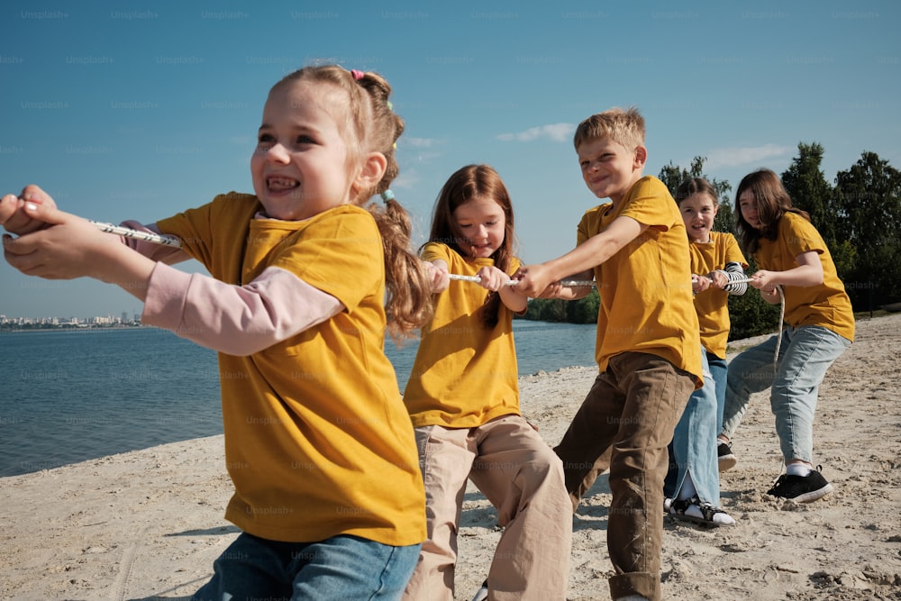 Um grupo de crianças brincando de cabo de guerra na praia
