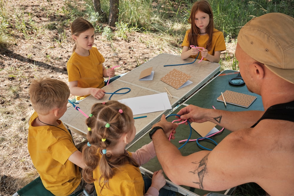 a group of children sitting at a table working on crafts