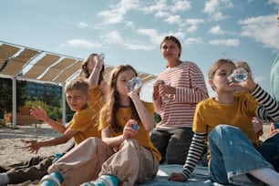 a group of children sitting on the ground drinking water