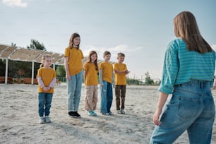 a group of children standing on top of a sandy beach