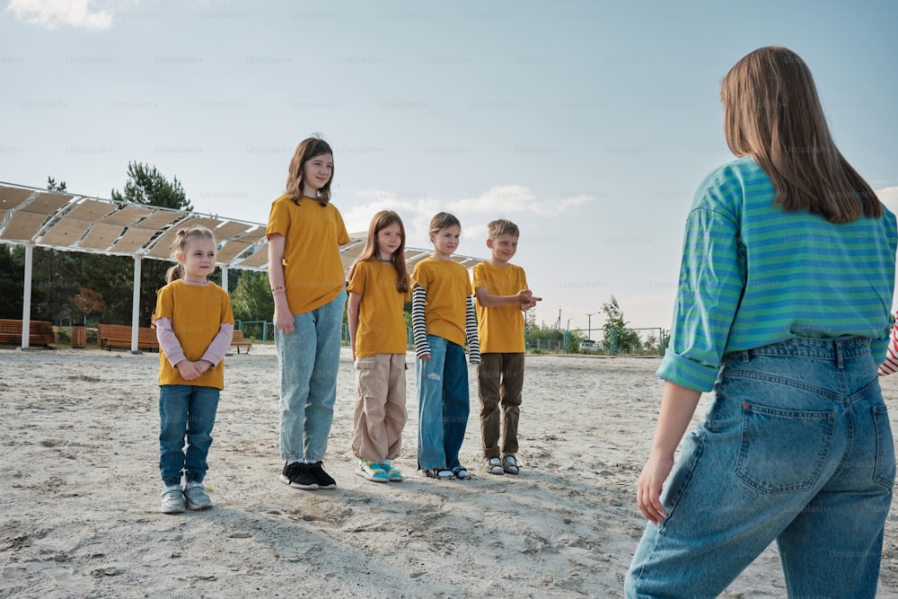 um grupo de crianças em pé em cima de uma praia de areia