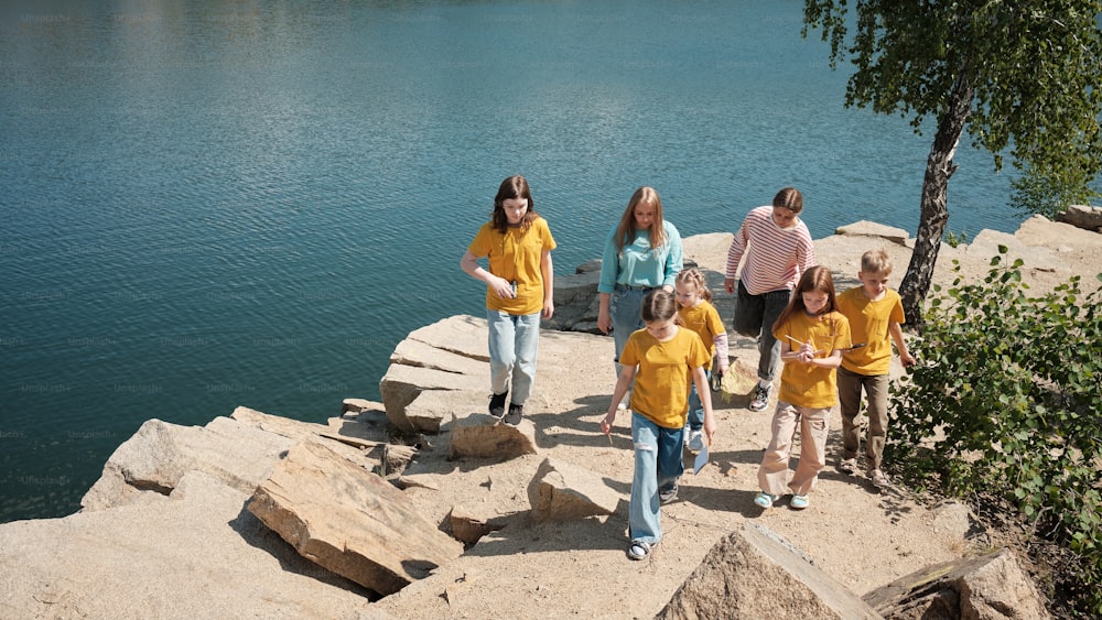 a group of people standing on top of a cliff next to a body of water