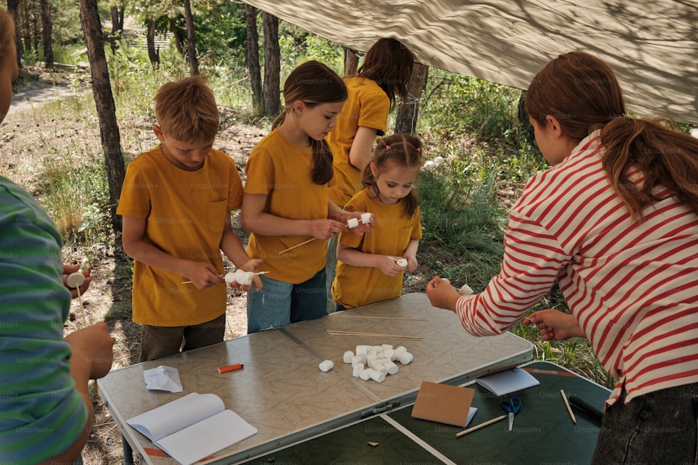 a group of people standing around a table with marshmallows