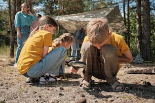 a couple of kids sitting on the ground next to a tent