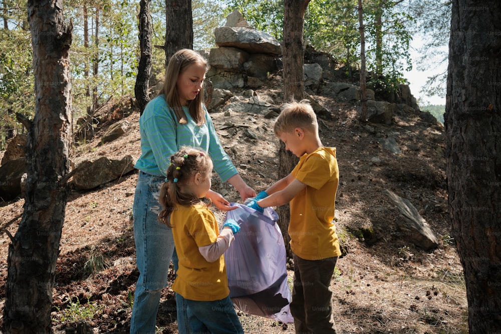 a woman helping two children put on a dress