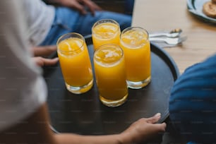 three glasses of orange juice on a tray