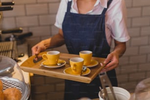 a woman holding a tray with two cups of coffee