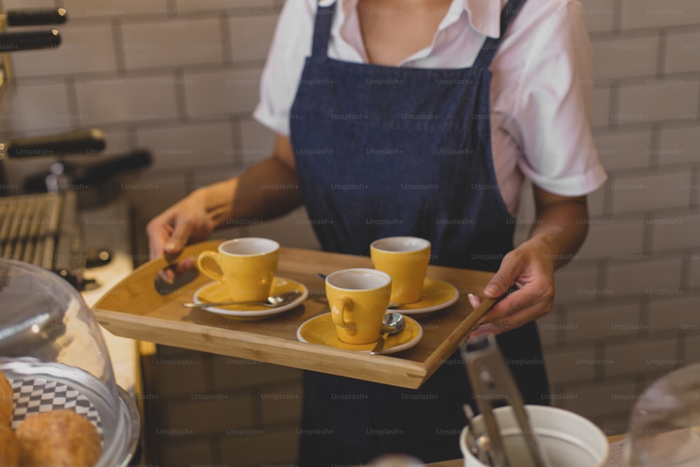 a woman holding a tray with two cups of coffee