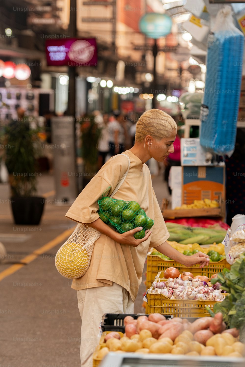 uma mulher em pé em frente a uma exposição de frutas e legumes