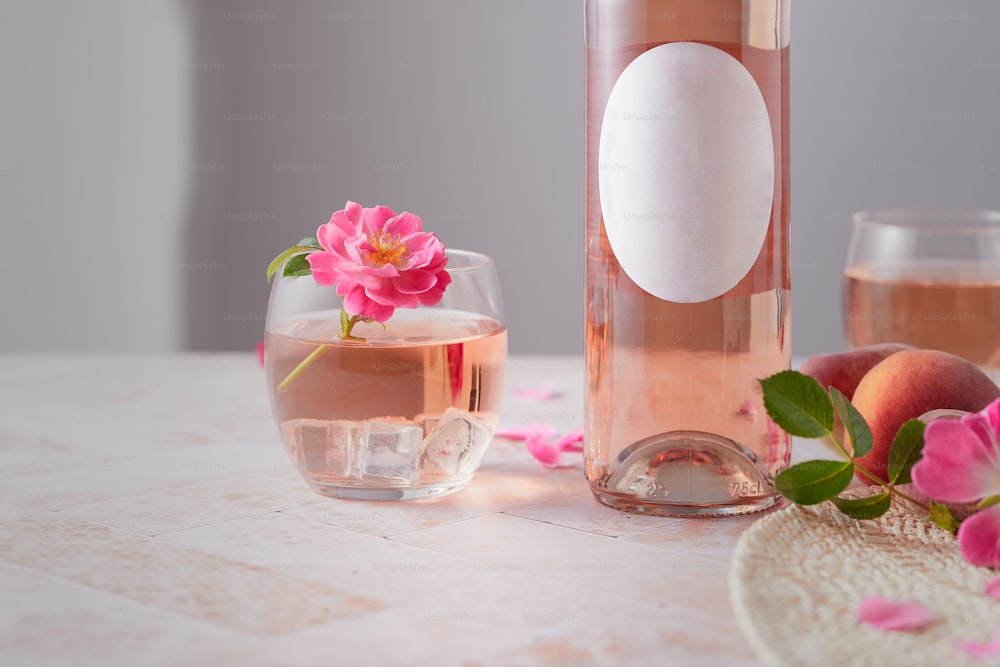 un bicchiere di vino rosato accanto a una bottiglia di vino