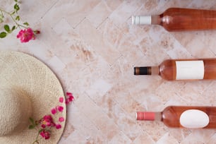 three bottles of wine sitting next to a straw hat