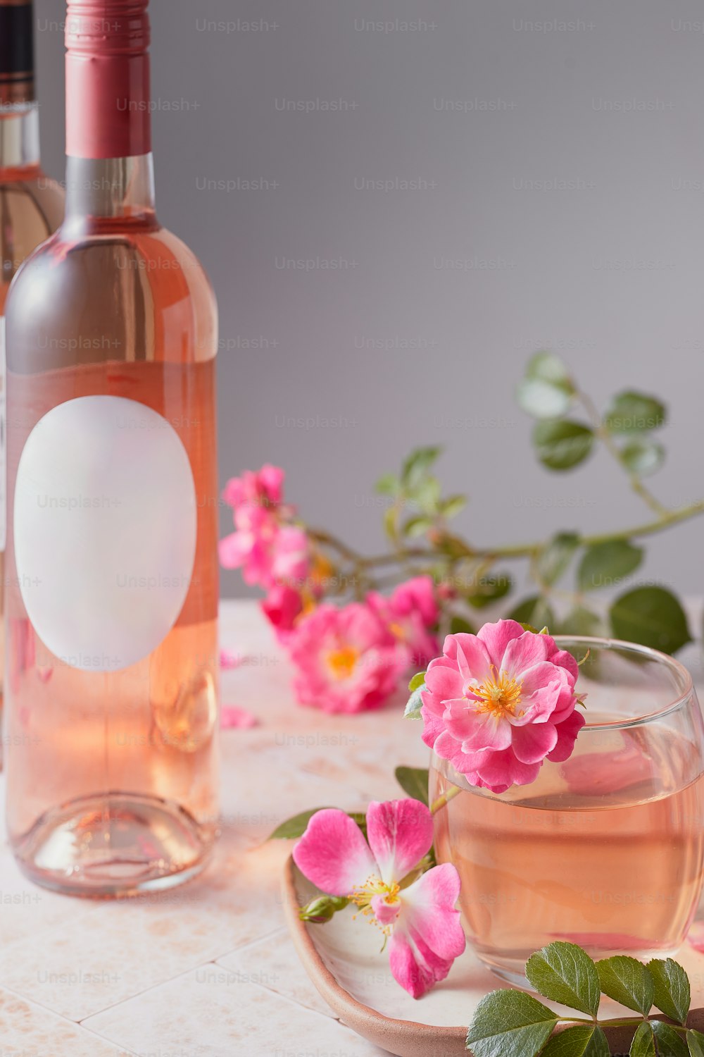 um copo de vinho rosa ao lado de uma garrafa de vinho