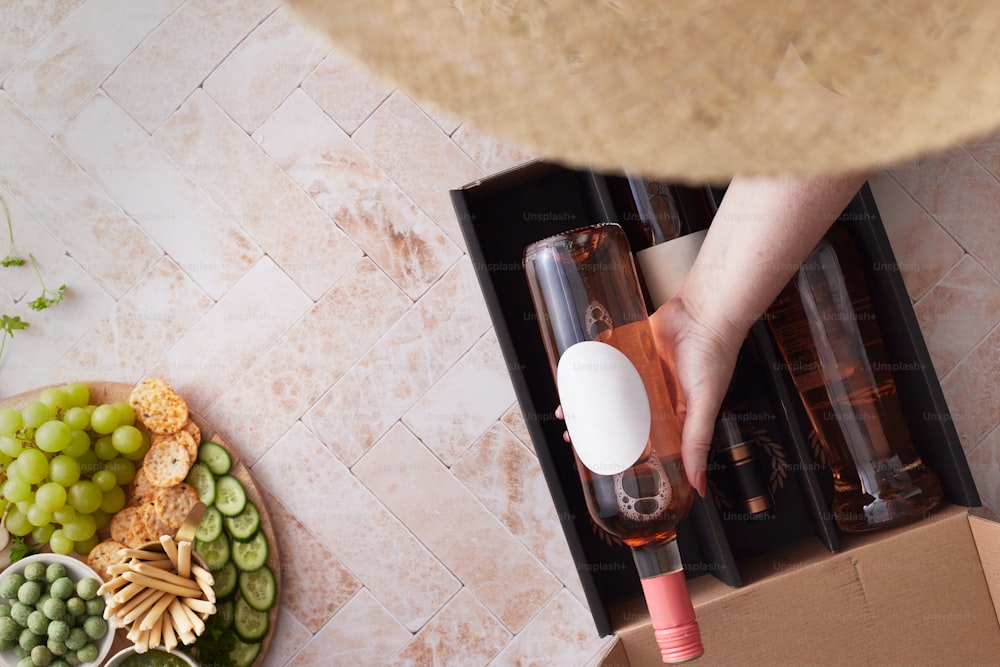 a person holding a wine glass next to a box of wine